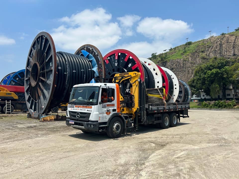 Munck carregando bobinas de cabo elétrico na carroceria